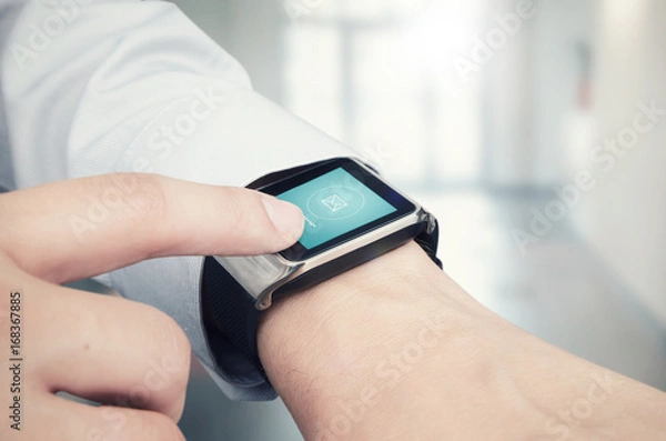 Fototapeta Businessman checking e-mail on smart watch. Office in background