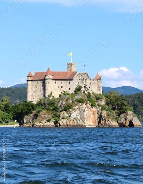 Fototapeta Medieval castle on an island, blue water, clear sky