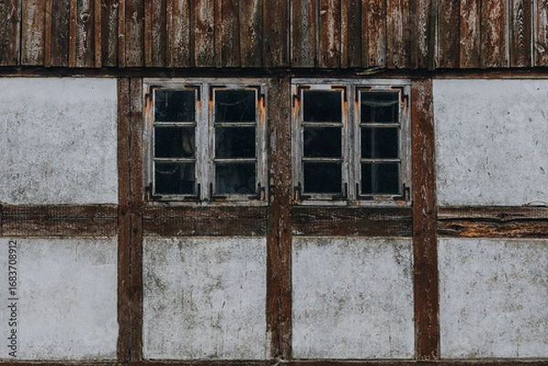 Fototapeta Weathered timber-frame windows on rustic wall