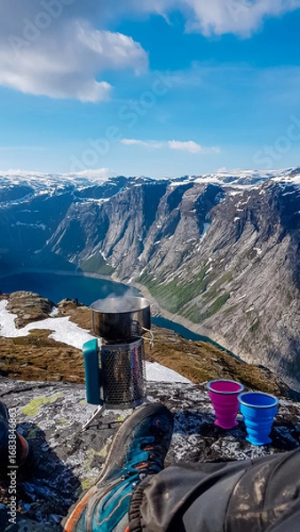 Obraz A hiker's point of view, relaxing with a camping stove boiling water for a warm drink. The setup overlooks the breathtaking Ringedalsvatnet fjord and snow-capped mountains in the Norwegian wilderness.