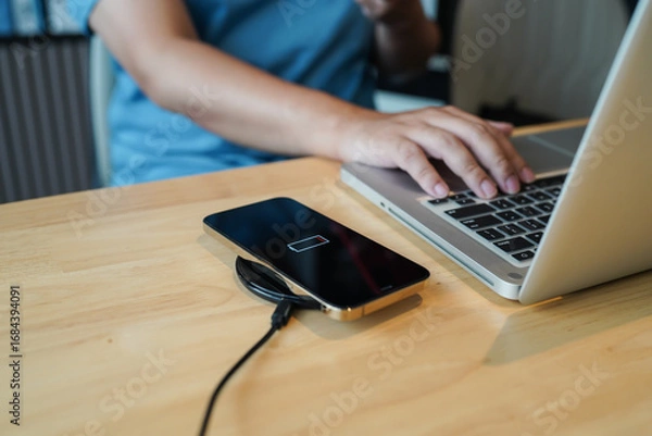 Fototapeta Charging mobile phone battery with wireless charging device in the table. Smartphone charging on a charging pad. Mobile phone near wireless charger Modern lifestyle technology concept