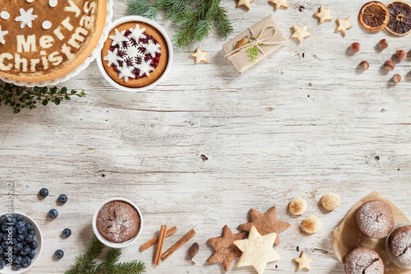 Fototapeta Christmass preparation concept. New Year composition with snowflakes, sweets, cinnamon, on a beige wooden background. Image for greeting card. Top view. Copy space.
