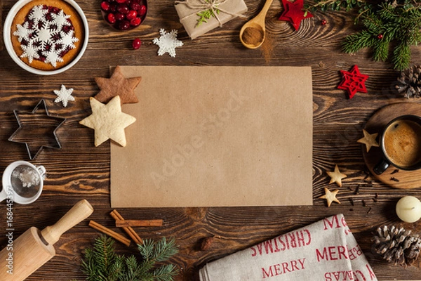 Fototapeta Christmass symbols sweets, candle, cinnamon, snowflakes and empty piece of paper on center. Christmass background with branches of furry spruce, cup of coffee on a wooden background.