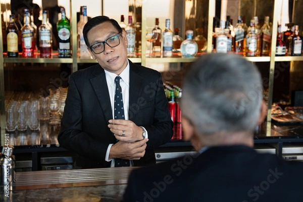 Fototapeta Attractive salesman, cashier serving customers at a retail store counter or bar restaurant counter.	