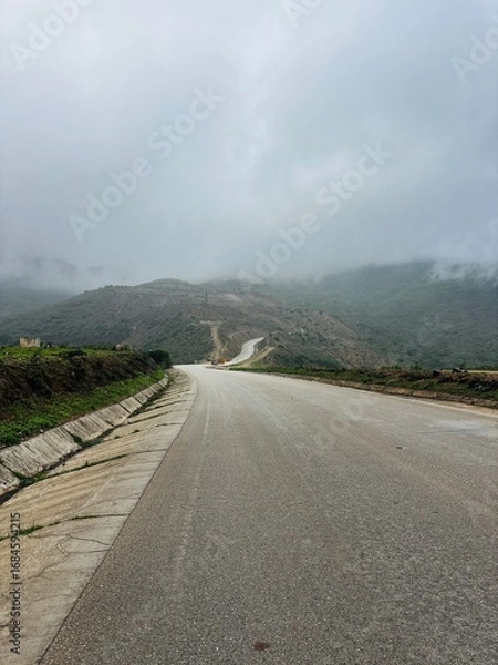 Fototapeta Scenic view of Magnetic Road, Salalah, Oman, featuring a winding road through lush green hills and rocky landscapes. A serene travel and nature destination in Dhofar. Oman another Kerala in gulf GCC