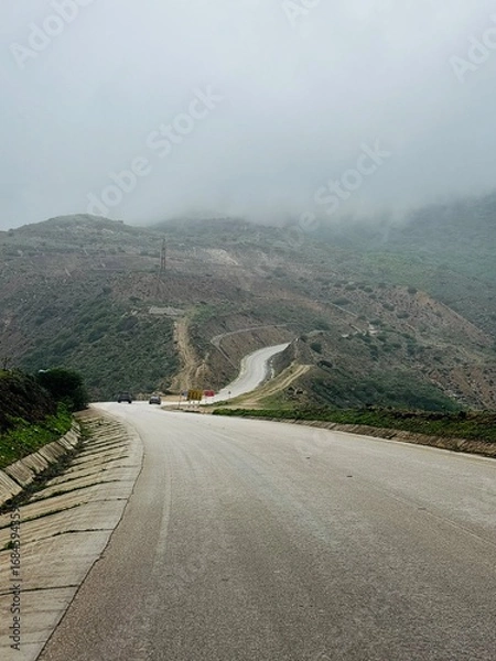 Fototapeta Scenic view of Magnetic Road, Salalah, Oman, featuring a winding road through lush green hills and rocky landscapes. A serene travel and nature destination in Dhofar. Oman another Kerala in gulf GCC