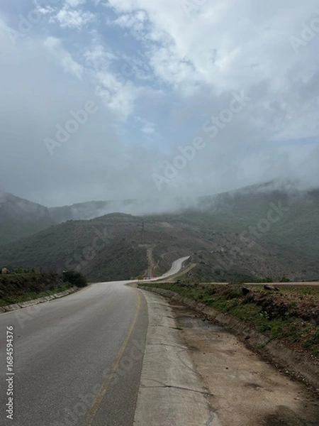 Fototapeta Scenic view of Magnetic Road, Salalah, Oman, featuring a winding road through lush green hills and rocky landscapes. A serene travel and nature destination in Dhofar. Oman another Kerala in gulf GCC