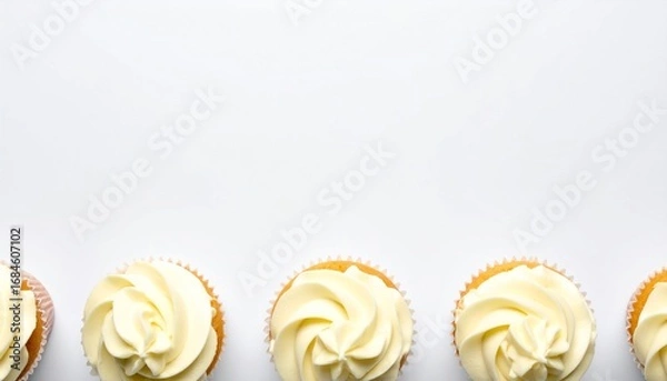 Fototapeta A row of cupcakes with white frosting, arranged along the bottom edge against a plain white background.
