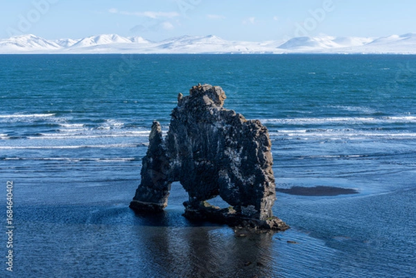 Fototapeta Rock Formation in Ocean with Snowy Mountains