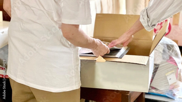 Fototapeta 断捨離中にダンボール箱を開けて見る2人の手元