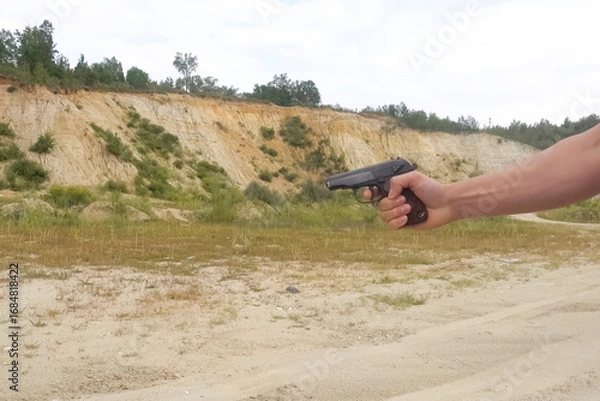 Fototapeta Shooting from blank Makarov pistol in nature against the background of a ravine.