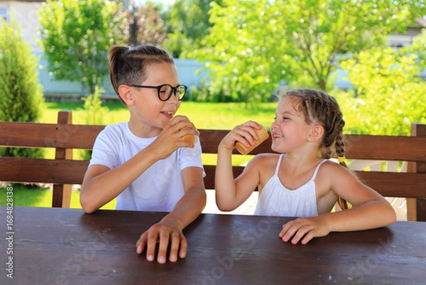 Fototapeta two children savoring ice cream cones while enjoying a sunny day outdoors