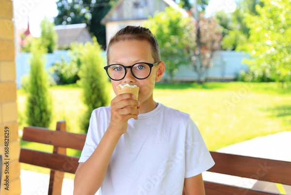 Fototapeta a teenager savoring a delicious ice cream cone while surrounded by the beauty of nature on a warm summer day.