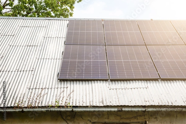 Obraz Modern solar panels mounted on an old corrugated metal roof, representing renewable energy, sustainable power, and eco-friendly technology