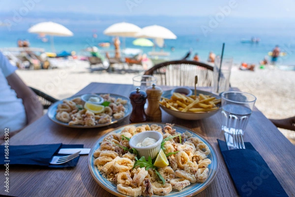 Fototapeta eating fried squid calamari with a sea view from the beach bar in croatia