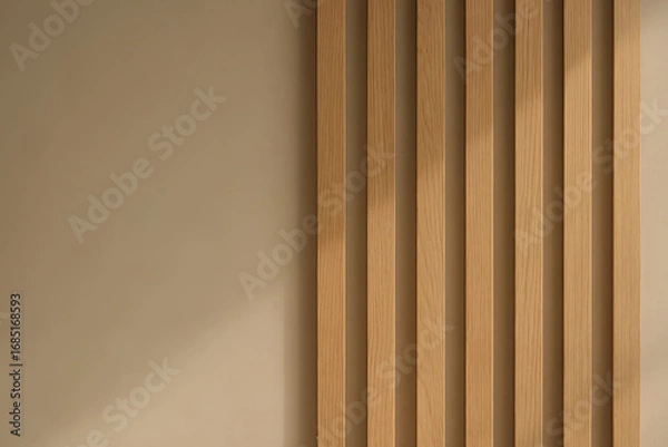 Fototapeta Vertical wooden slats aligned on the right side of a plain beige wall, captured in natural lighting with soft shadows, representing minimal interior design concept. Background