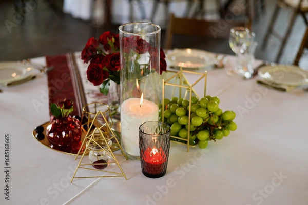 Obraz Banquet table for a wedding or anniversary. Red roses. Classic layout. Glasses and white plates. In the fresh air