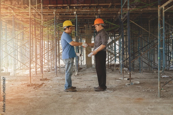 Fototapeta Engineer discussing with foreman about project in building construction site