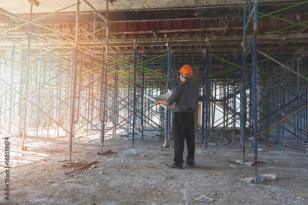 Fototapeta Engineer with blueprint in building construction site