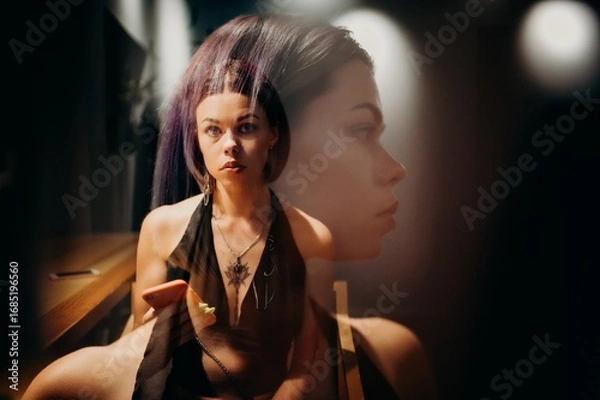 Fototapeta Creative portrait of a woman captured with double exposure, combining her direct gaze and side profile. Dramatic light and shadows enhance the surreal and artistic mood of the composition.
