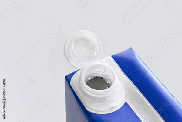 Fototapeta Tethered carton cap closeup on white. Plastic caps remain attached to a carton after opening. Reduce plastic pollution and recycle concept.