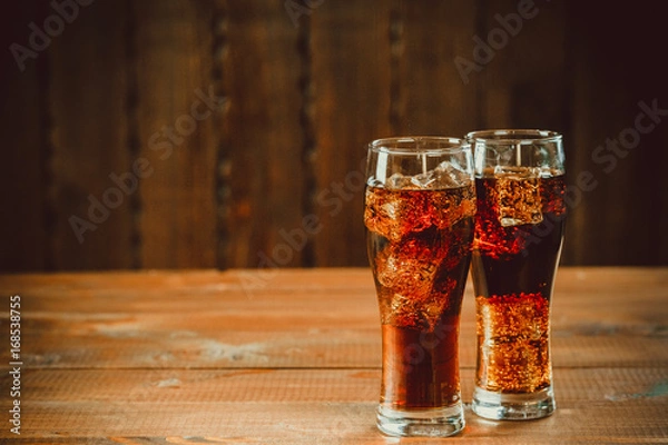 Obraz Piękny zimny gazowany cola soda z kostkami lodu w szklankach kielich na starym drewnianym tle z wolnej przestrzeni