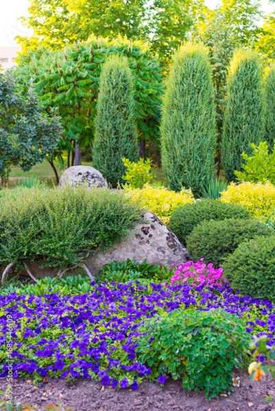 Fototapeta Colorful flower garden. A serene garden blooms with colorful flowers and lush greenery, creating a peaceful atmosphere in bright sunlight.