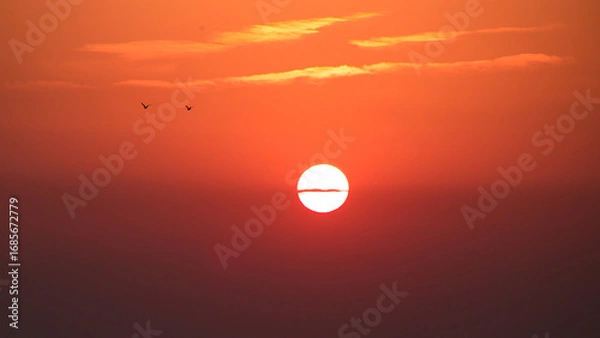 Fototapeta Sunset with red and orange sky and sun in center