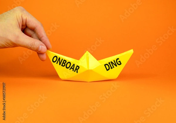 Fototapeta Onboarding success symbol. Concept word Onboarding on beautiful yellow paper boat. Beautiful orange background. Businessman hand. Business onboarding success concept. Copy space.