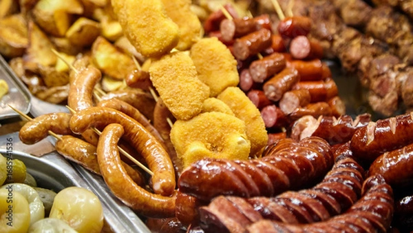 Fototapeta Assorted grilled meats and snacks displayed on a tray, featuring sausages, skewers, and fried items, showcasing a vibrant culinary feast for food lovers