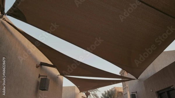 Obraz Three triangular shade sails provide coverage in a calm residential courtyard. Serene outdoor setting enhances peaceful atmosphere during daytime.