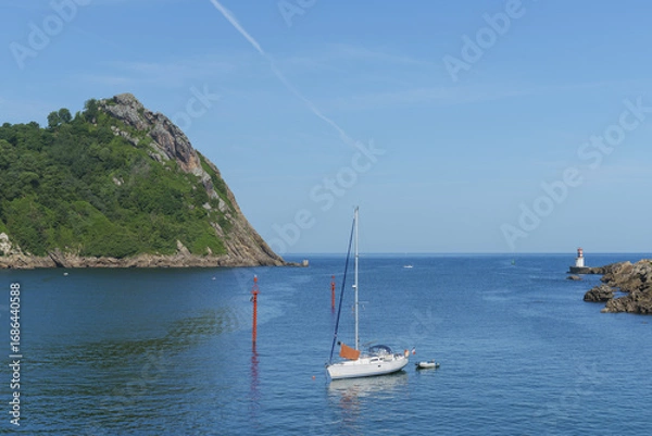 Fototapeta Sailboat anchored in Pasaia Bay with the La Plata lighthouse in the background, Basque Country