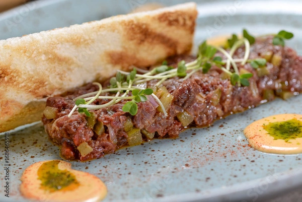 Fototapeta veal tartare with microgreens in a plate of bruschetta macro photo