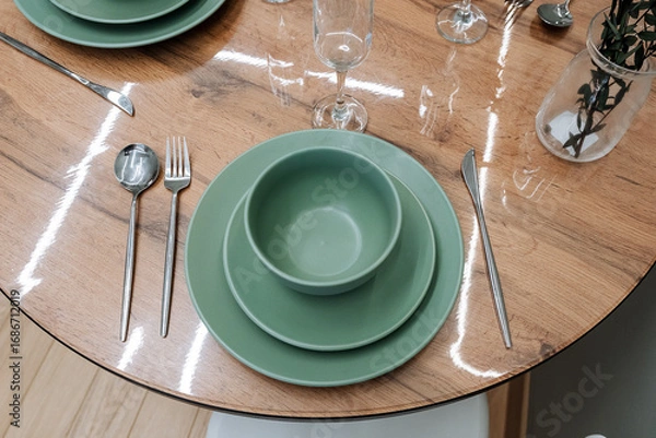 Fototapeta An Elegant Green Dinner Set on a rustic Wooden Table, showcasing a stylish Dining Arrangement ideal for gatherings or special occasions, complete with exquisite glassware
