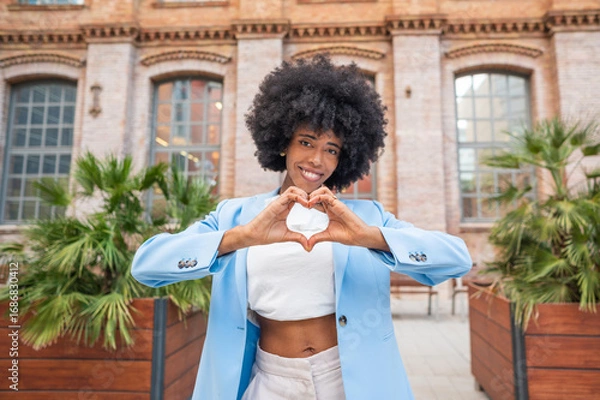 Fototapeta Young manager showing heart with hands in front of office building