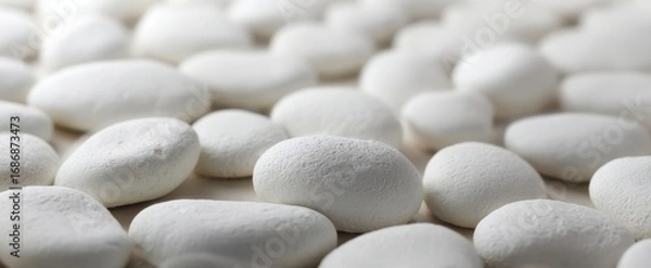 Fototapeta The white oval tablets arranged in a soft focus macro pattern on white background