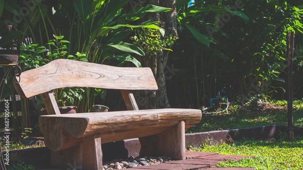 Fototapeta Wooden bench on the ground and many green plants in the garden, perspective side view with copy space