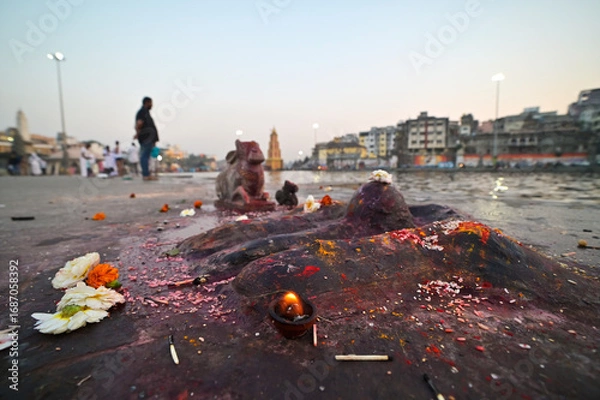 Fototapeta Fire burning in front of a small Shiva Lingaa as a part of Hindu rituals on the Ghats of River Godavari, Nasik, Maharashtra, India.