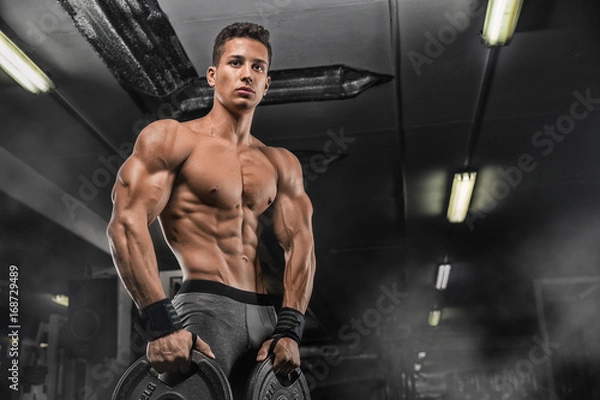 Fototapeta Handsome man with big muscles, posing at the camera in the gym