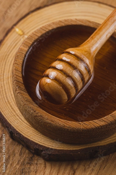 Fototapeta A jar of honey and a spoon, honey is pouring