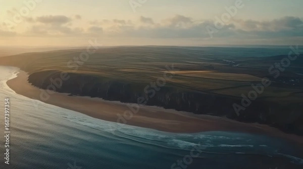 Fototapeta Aerial view capturing the convergence of the sea cliff and land during twilight creating a serene