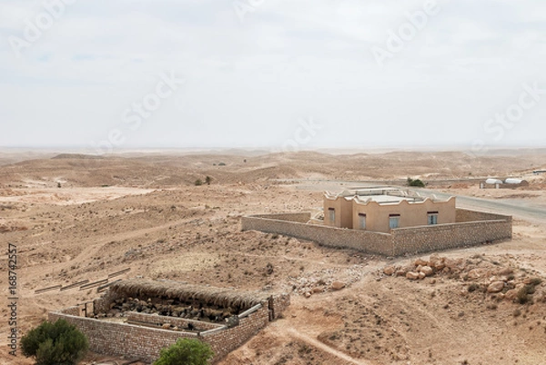 Obraz Sheepfold and a building in the middle of an arid desert with a horizon line