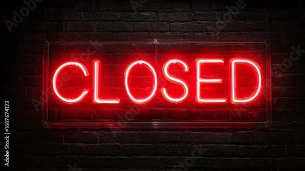 Fototapeta A vibrant neon sign illuminates the word "CLOSED" against a dark brick wall, signaling closure or inactivity.