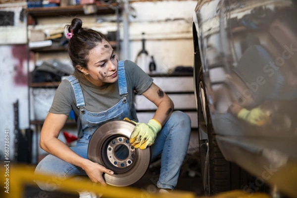 Obraz A young mechanic carefully installing a brake rotor, exemplifying precision and skill in automotive repair work.