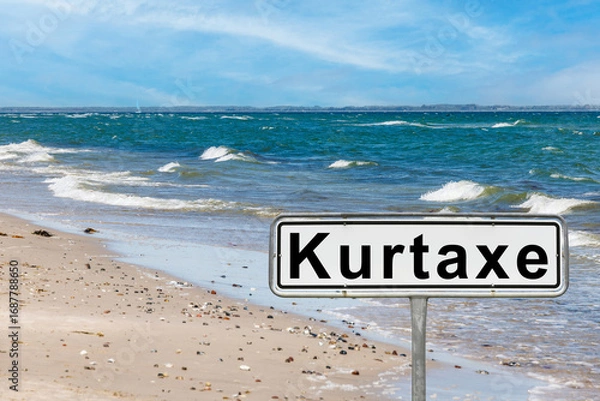 Fototapeta Kurtaxe sign on sandy beach with ocean waves crashing