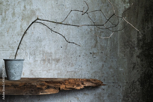 Fototapeta Minimal branch in metal pot on rustic wood shelf against textured wall, capturing wabi sabi beauty in natural simplicity.