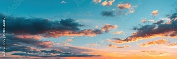 Fototapeta Wide-angle view of a dramatic sunset sky, filled with varied clouds of orange, pink, and blue tones