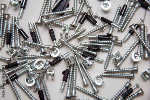 Fototapeta Furniture fasteners are poured out in a heap on furniture parts. Preparation for the assembly of cabinet furniture, unpacking and laying out fasteners and furniture parts