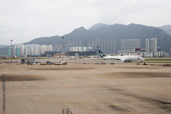 Fototapeta Exterior architecture buildings of Hongkong international airport and Aircraft boeing stop waiting passenger journey and local crew worker prepare plane on runway on April 26, 2025 in Hong Kong, China
