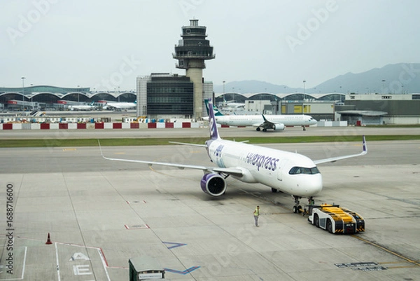 Fototapeta Exterior architecture buildings of Hongkong international airport and Aircraft boeing stop waiting passenger journey and local crew worker prepare plane on runway on April 26, 2025 in Hong Kong, China